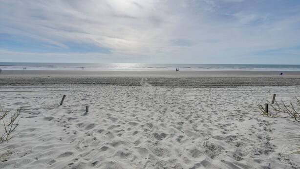 A beach with a sandy foreground and a calm sea in the background.