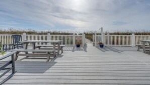 A wooden deck with picnic tables and benches, a white picket fence, and a sign prohibiting grilling.