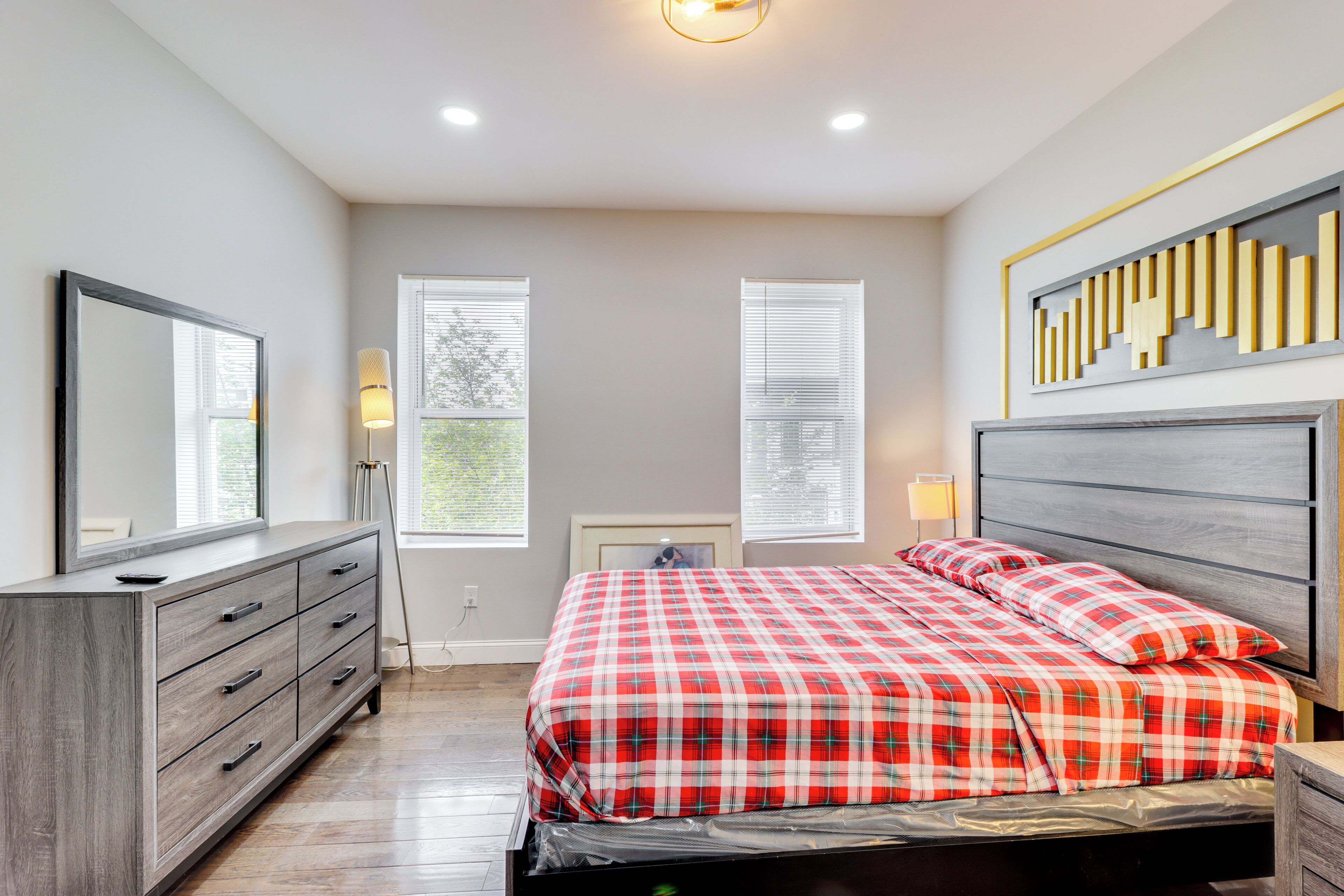 Quarto com cama, cómoda e luminária na parede.