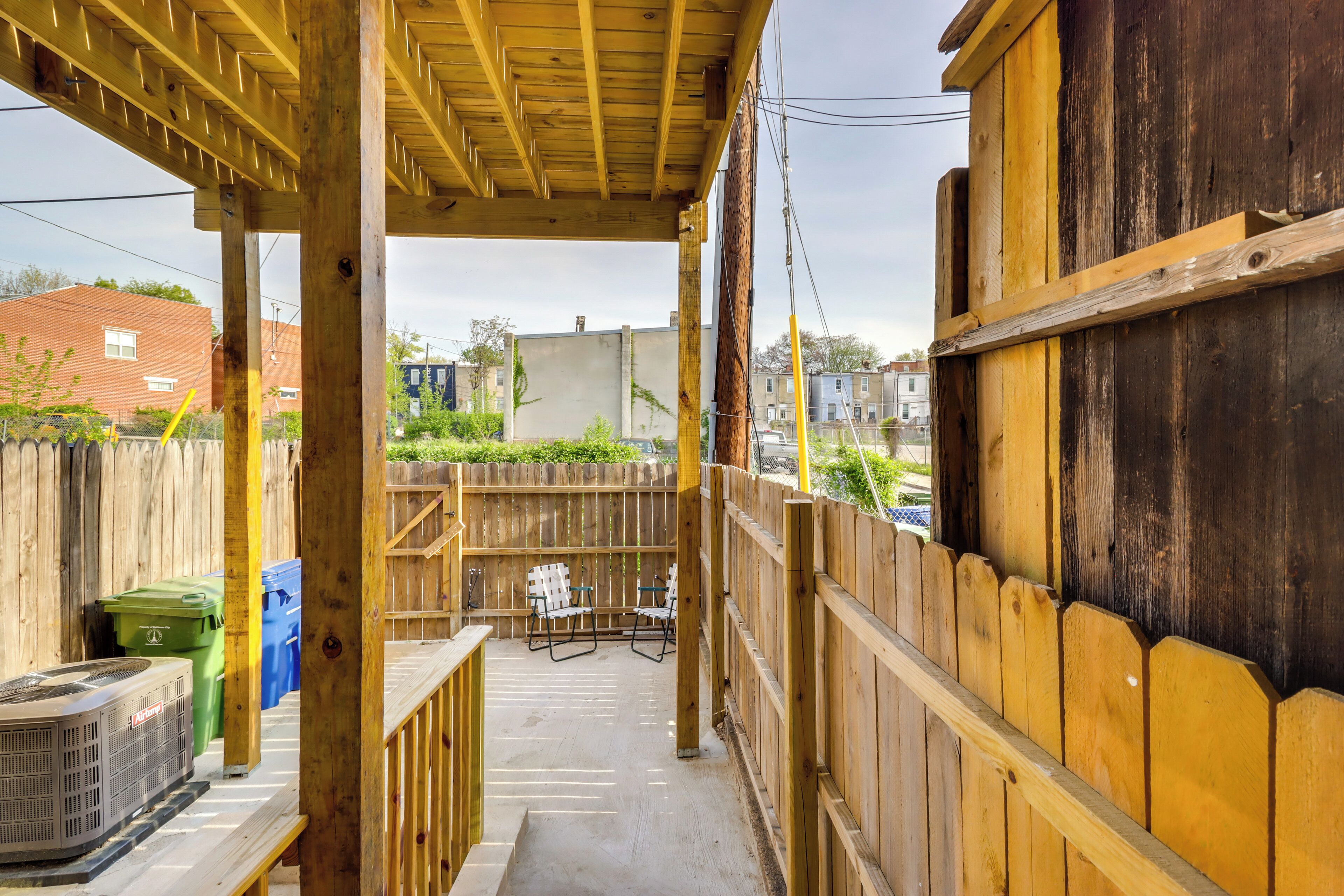 A covered outdoor area with a wooden deck, a concrete floor, and a view of a residential neighborhood.