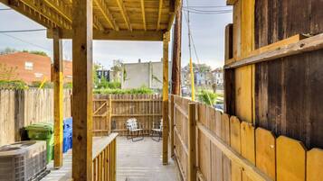 A covered outdoor area with a wooden deck, a concrete floor, and a view of a residential neighborhood.