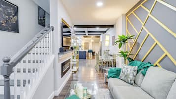 A modern interior with a staircase, a sofa, a dining area, and a kitchen.