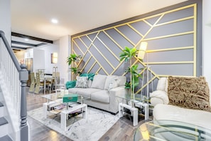 A modern living room with a sofa, coffee table, and decorative plants. - Newly Renovated Abode w/ Patio in Baltimore! (Baltimore)