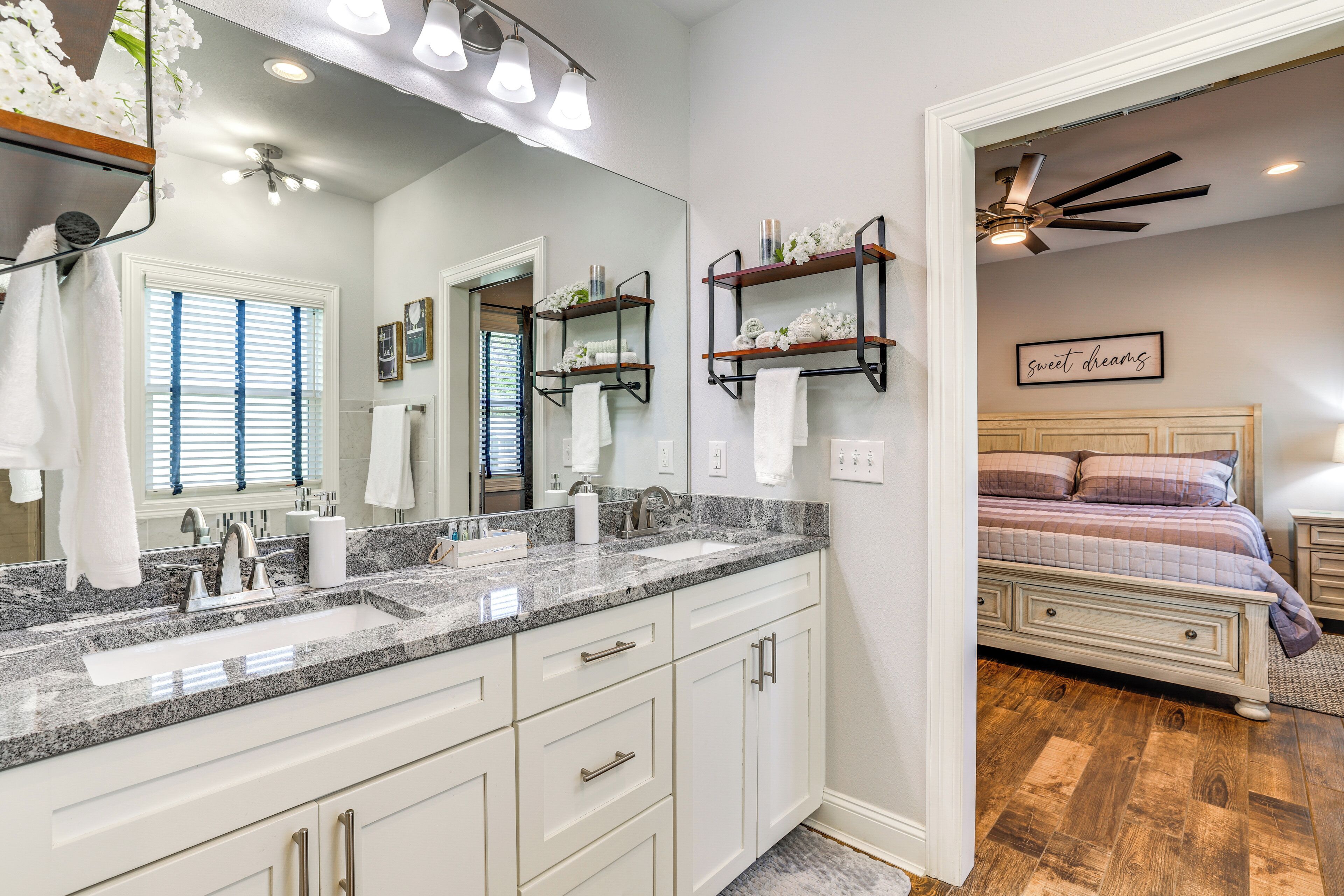 A modern bathroom with a large mirror, dual sinks, and a vanity with drawers.