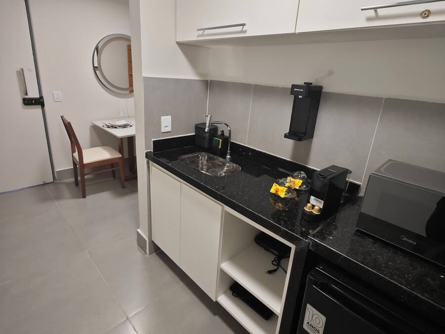 A modern kitchen with white cabinets, a black countertop, and a built-in dishwasher.