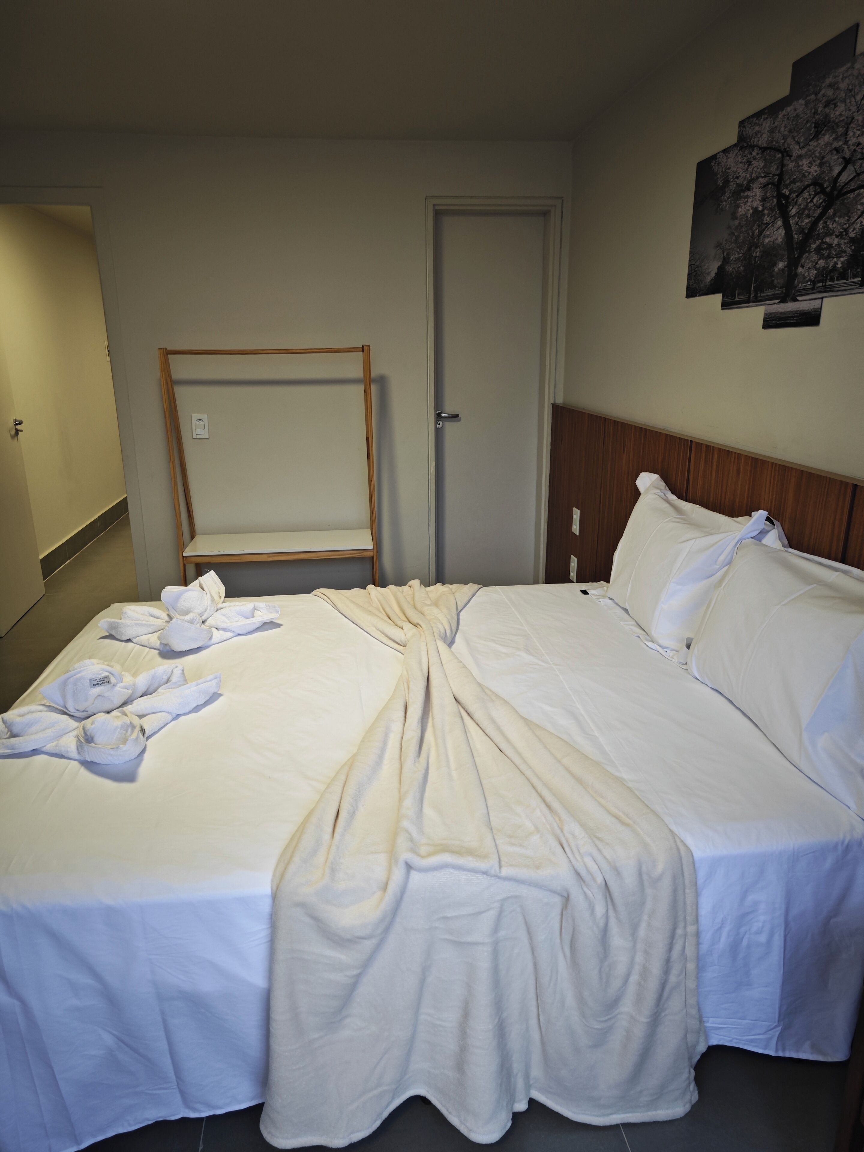 Una camera d'albergo con un letto grande, una testiera in legno e uno specchio appeso al muro.