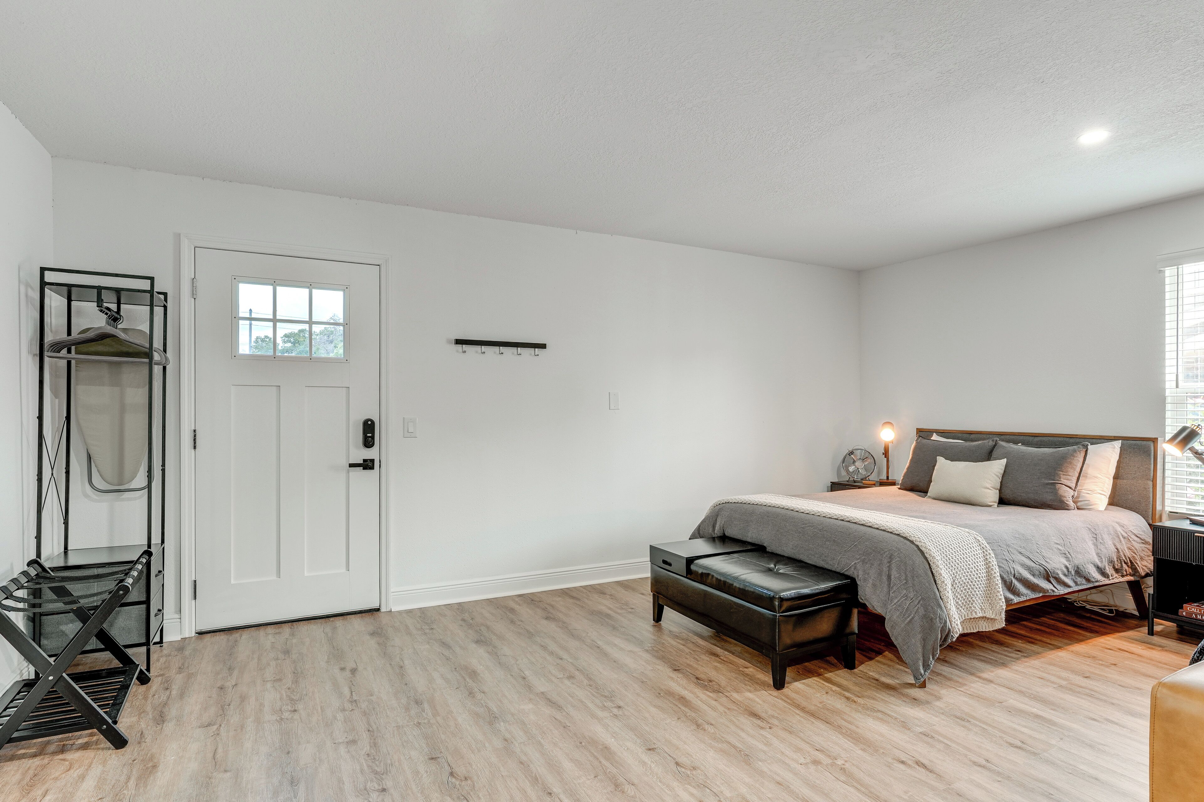 Quarto com cama, banco, guarda-roupa e porta.