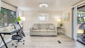 A modern office space with a glass table, black office chairs, a beige sofa, and a small side table with a lamp. - Golf & Pool Access: Home w/ Yard in Lady Lake (Lady Lake)