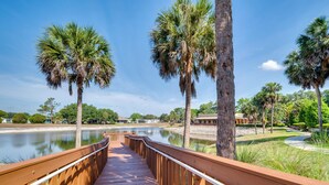 A wooden boardwalk leading to a body of water, surrounded by palm trees and a clear sky. - Golf & Pool Access: Home w/ Yard in Lady Lake (Lady Lake)