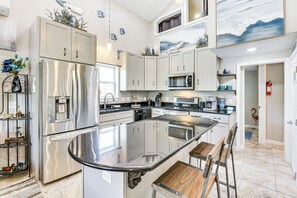 A modern kitchen with stainless steel appliances, a large island, and white cabinetry. - 13 Mi to St Andrews State Park: Cabin w/ Patio! (Panama City)