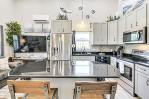 A modern kitchen with stainless steel appliances, a central island, and white cabinetry. - 13 Mi to St Andrews State Park: Cabin w/ Patio! (Panama City)