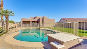 A swimming pool with a curved design, surrounded by a brick patio and a fence. - Private Pool + Patio: Desert Abode in Goodyear (Goodyear)