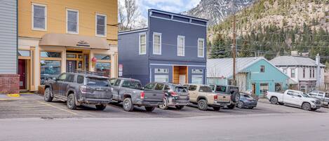 A row of parked vehicles in front of a building with a storefront.