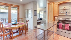 Una cocina moderna con armarios de madera, una estufa de acero inoxidable y una zona de comedor con una mesa redonda y sillas.