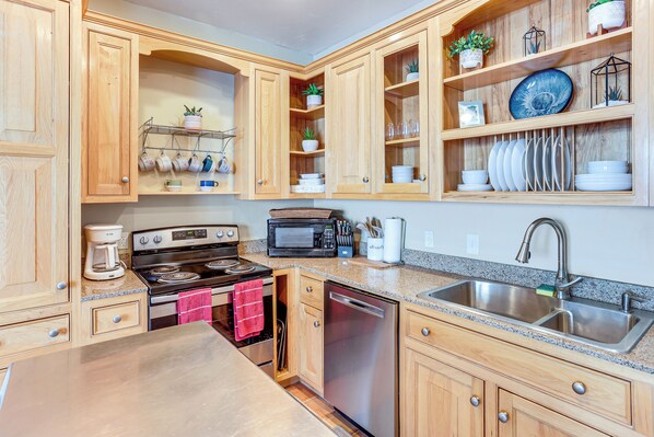 A kitchen with wooden cabinets, a stainless steel sink, a dishwasher, a microwave, and a stove.
