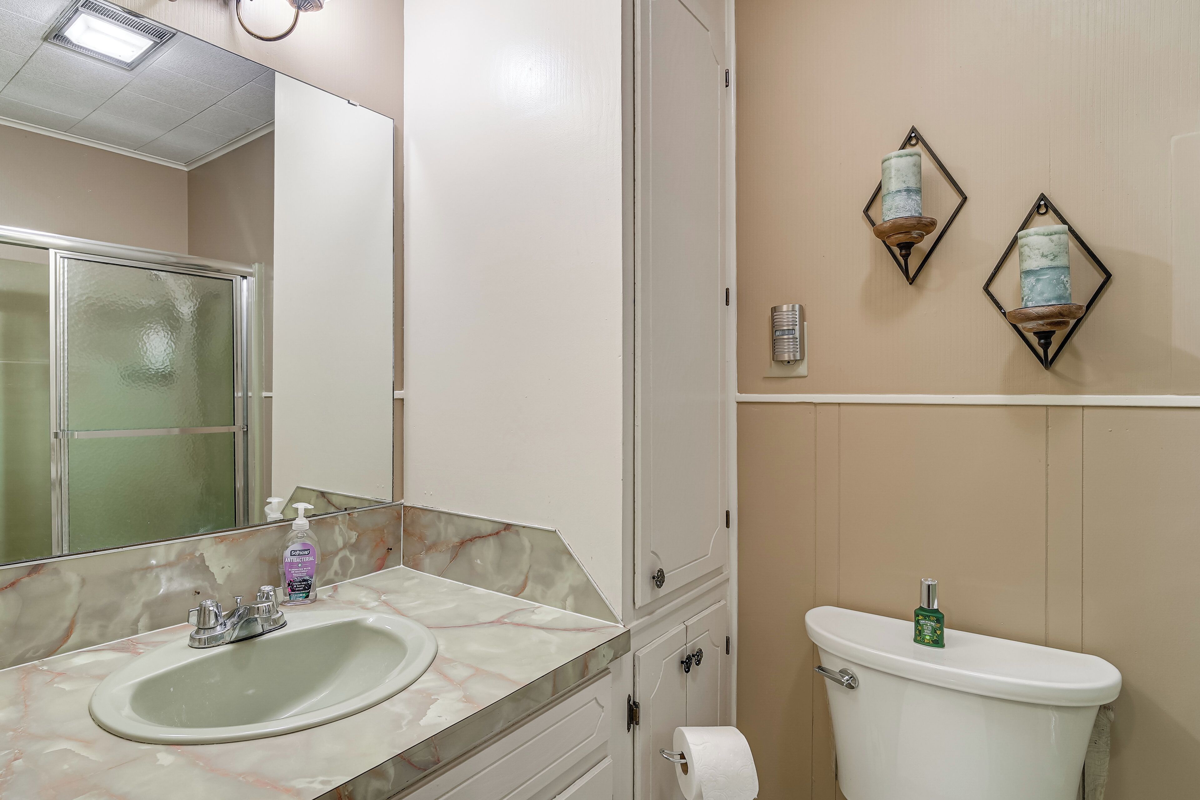 A bathroom with a marble sink, a toilet, and two wall-mounted sconces.