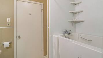 A bathroom with a toilet, sink, and bathtub. There are white shelves above the bathtub.