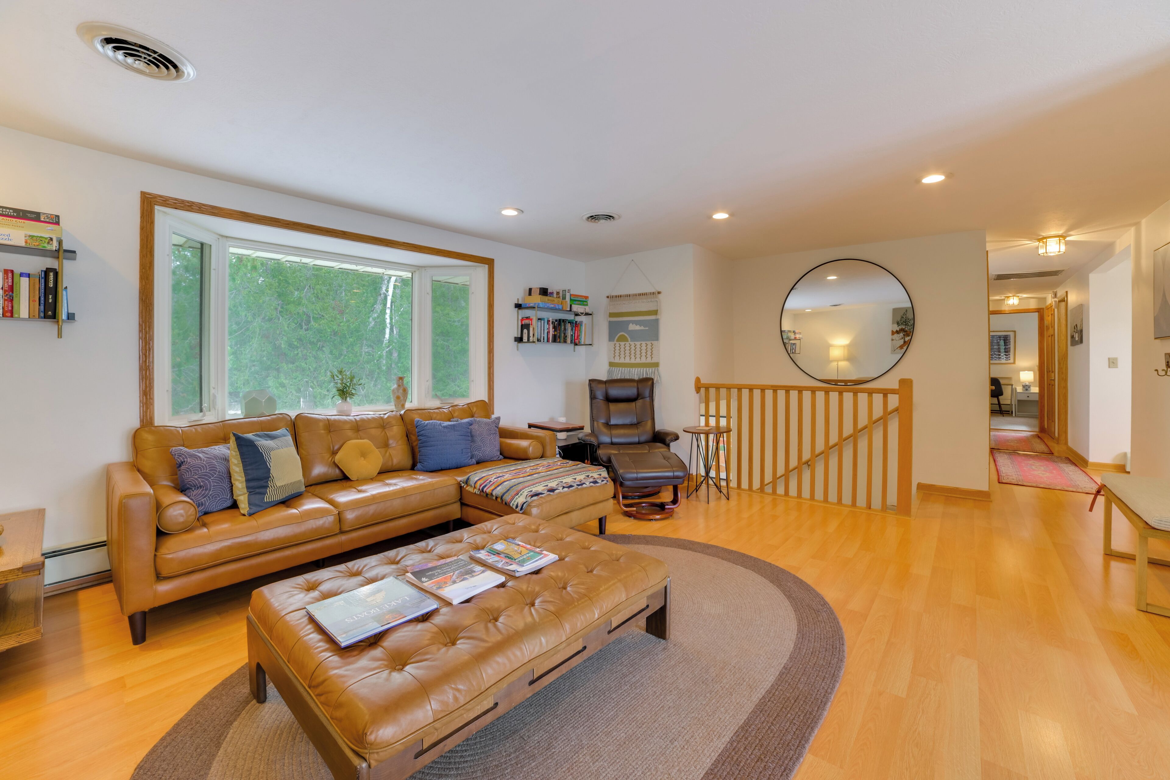 A spacious living room with a leather sofa, a matching ottoman, and a large window.