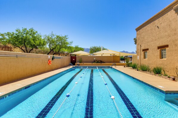 A swimming pool with clear blue water, surrounded by beige walls and a few trees. - Newly Renovated Home w/ Pool Access in Tucson! (Saddlebrooke)