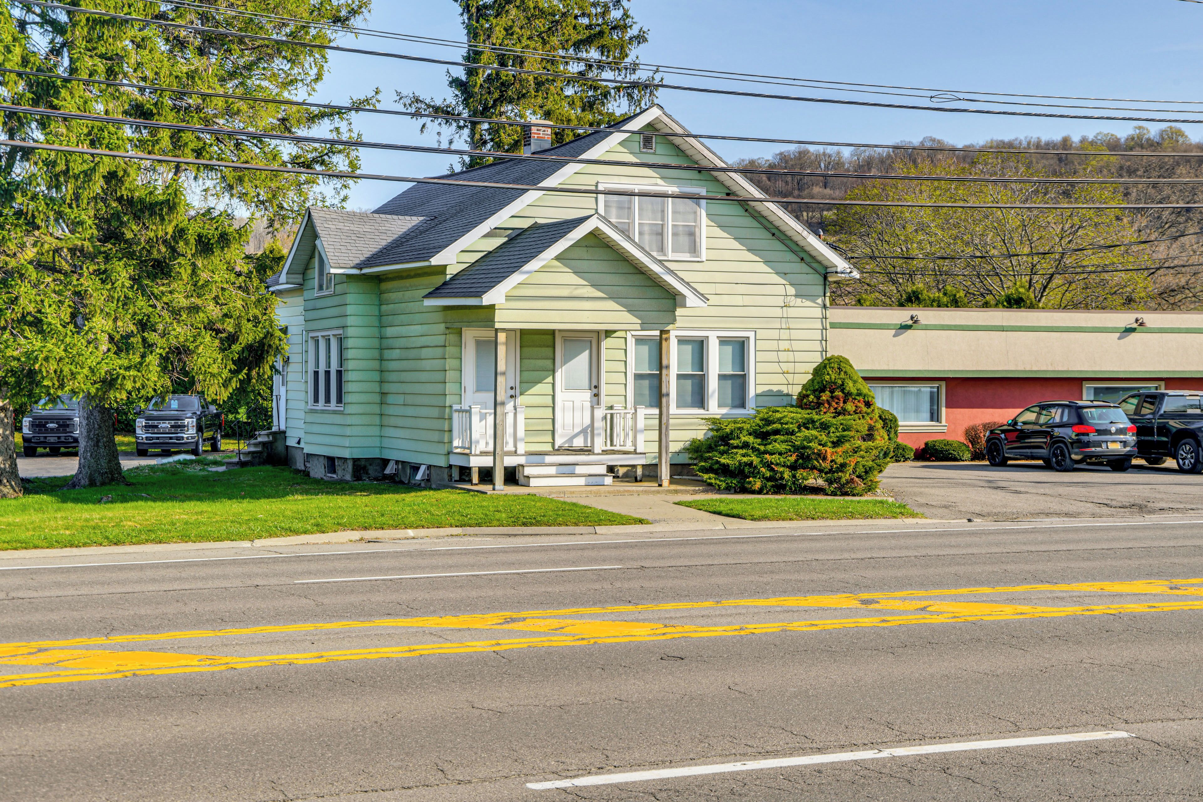 A two-story house with a front porch, a small front yard, and a street view.