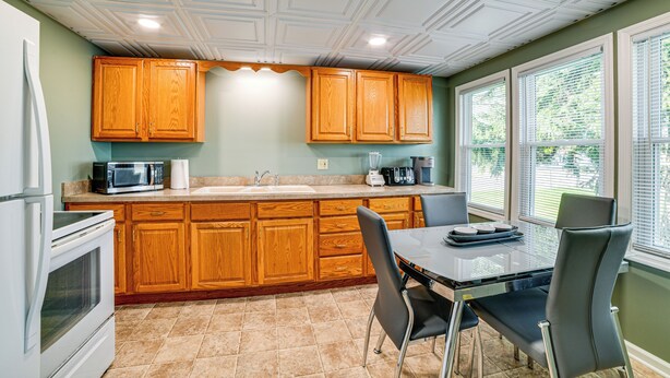 Una cocina con armarios de madera, un microondas, un fregadero y una mesa de comedor con sillas.