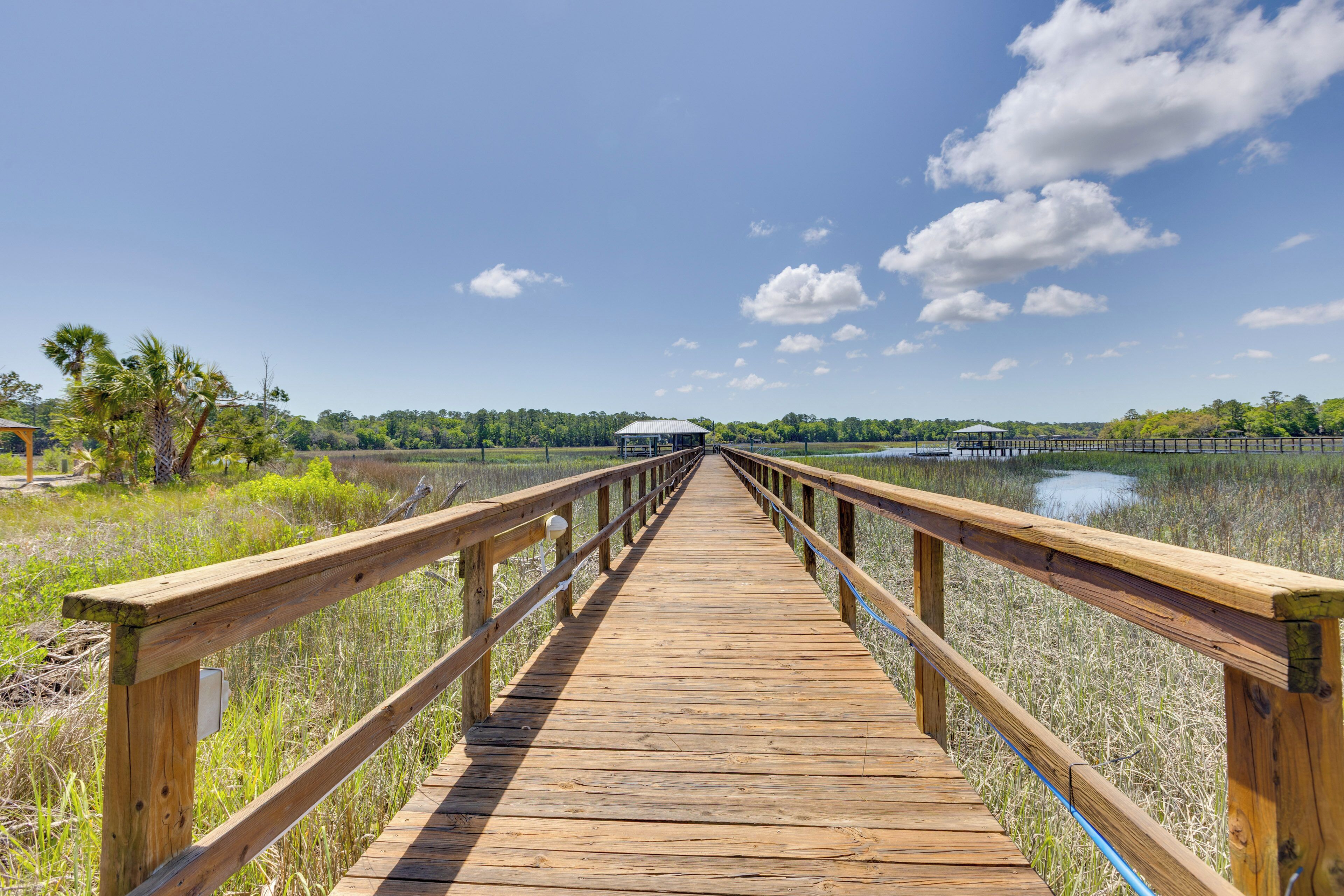A wooden boardwalk leading to a covered structure in a natural setting.