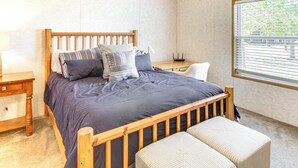 Camera da letto con un letto in legno, un comodino, una sedia e una finestra con persiane.