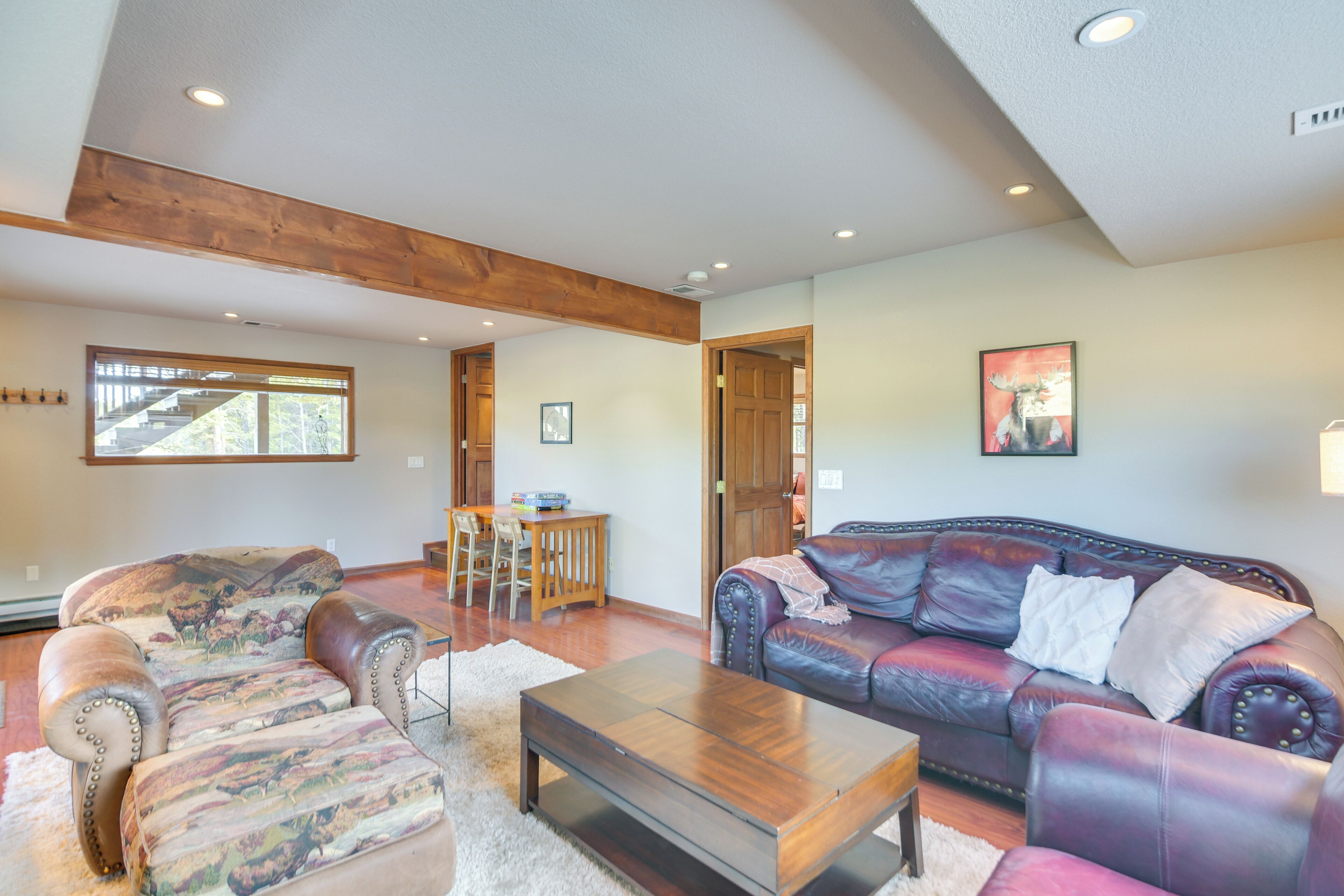 A spacious living room with a leather sofa, a wooden coffee table, and a dining area with a wooden table and chairs.