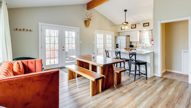 A spacious living area with a wooden dining table and benches, a red sofa, and a mounted deer head on the wall. - Beach Access: Bbq-ready Poconos Family Getaway! (Blakeslee)