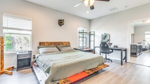 Un dormitorio con cama, escritorio, silla, ventilador de techo y ventana con persianas.