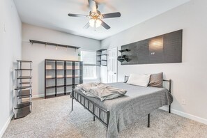 Ein Schlafzimmer mit einem Bett, einem Deckenventilator, einem Kleiderschrank und Regalen.