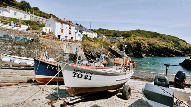 Un barco llamado 'Little Dot T021' amarrado en un puerto con casas al fondo.