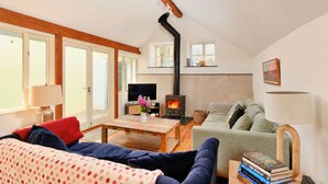 Una sala de estar acogedora con chimenea, un sofá, una mesa de centro y una televisión.