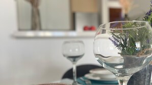A dining table set with plates, a glass, and a vase with dried flowers. - Celeste by the Sea: Summer Chill, Pool, Beach 2BR. (Paphos)