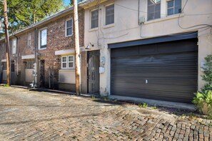 Une rangée de maisons de ville en briques, avec des portes de garage fermées, bordant une rue pavée.