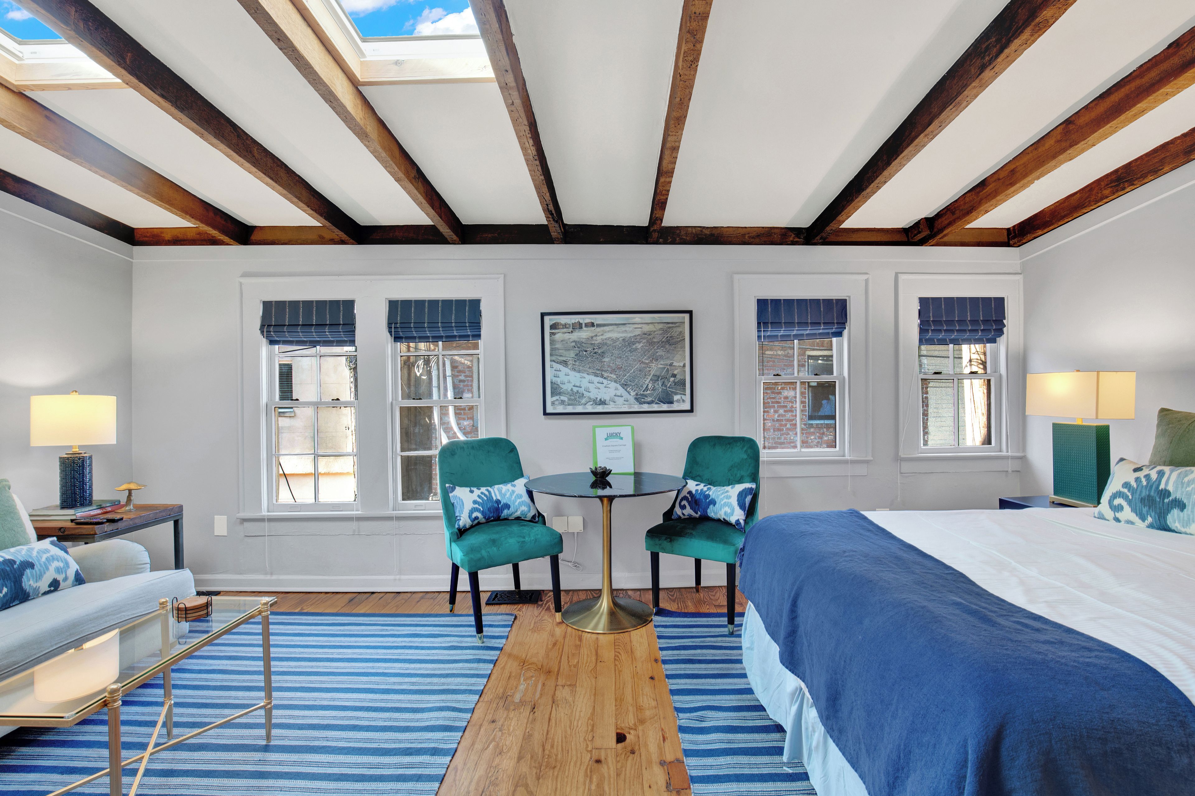 A bedroom with a large bed, two chairs, a small table, and a window with a view.