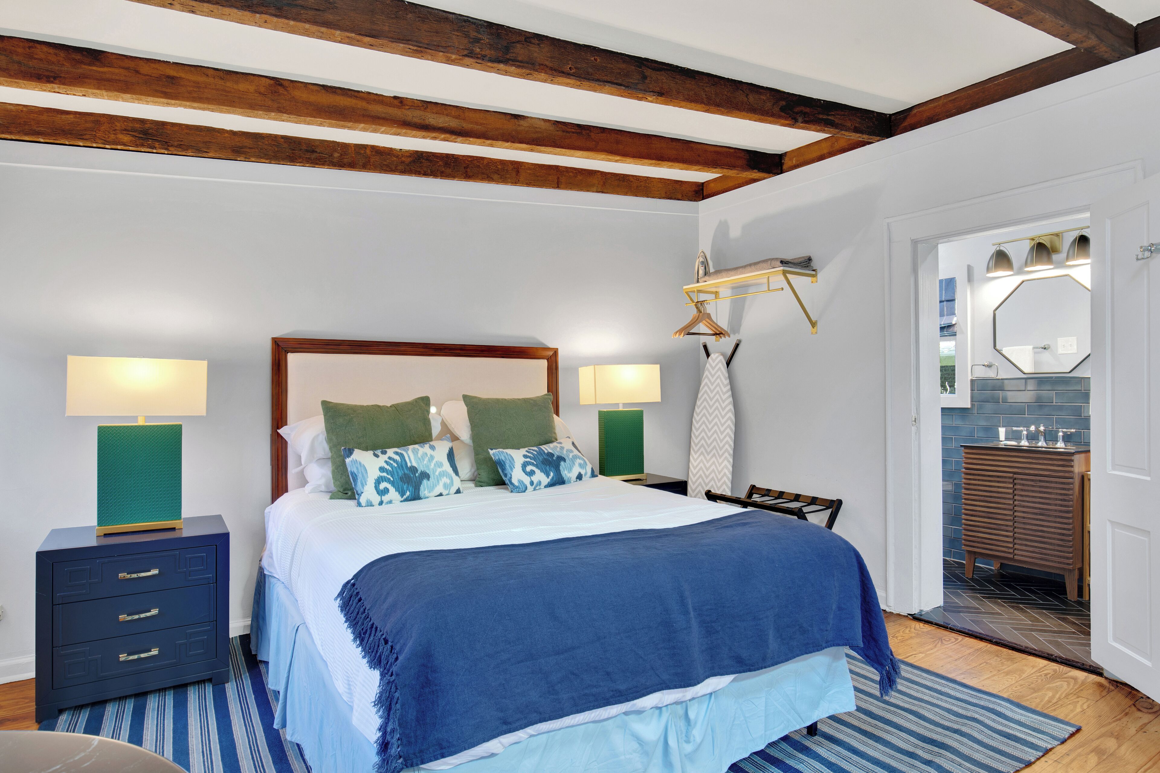 A bedroom with a large bed, two bedside tables, a dresser, and a mirror.