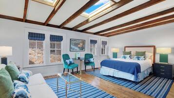 A spacious room with a large bed, a sofa, a dining table, and a skylight.