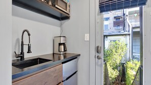 Une cuisine compacte équipée d’un évier intégré, d’une machine à café et d’un réfrigérateur.