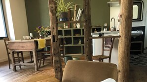 Een gezellige woonkamer met een ronde houten stoel, een eettafel en een keuken op de achtergrond.