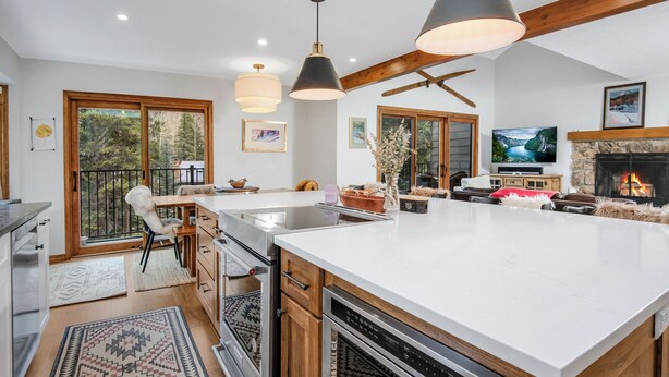 Une cuisine moderne dotée d’un grand îlot central, de fours encastrés et d’une cheminée en pierre.