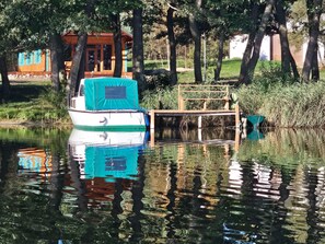 Ein Boot liegt an einem hölzernen Steg, im Hintergrund ein Gebäude.