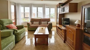Een woonkamer met een bank, fauteuil en tv-meubel.