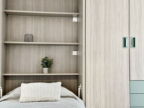 A bedroom with a bed, a bedside table, a wall-mounted shelf with a potted plant, and a wardrobe with a mirror. - El Rincón del mar - 30022 (Somo)