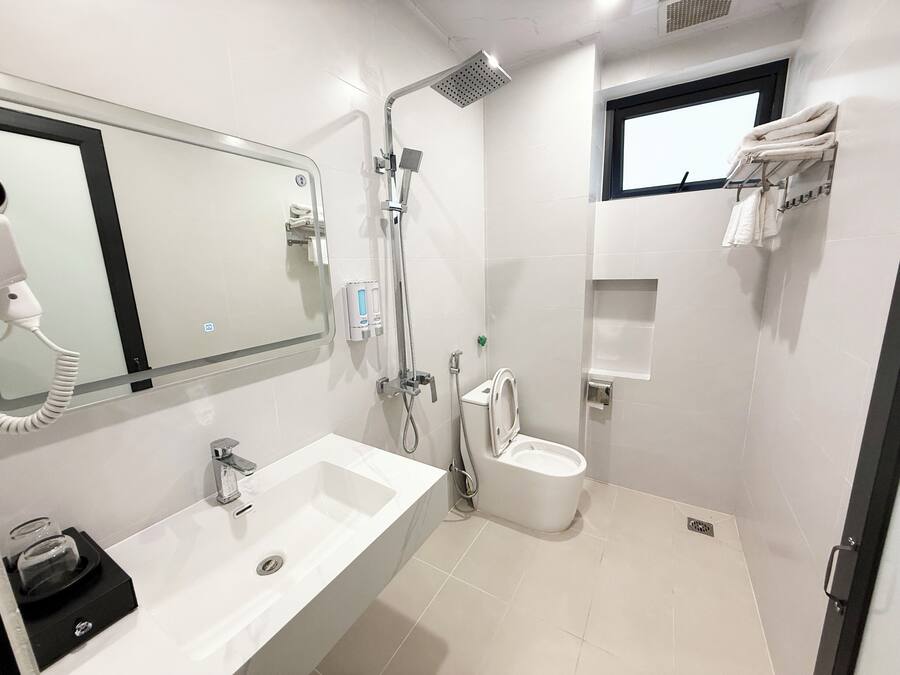 A modern bathroom with a large mirror, a sink, a toilet, and a shower.