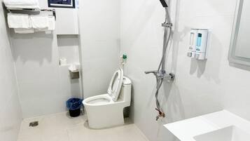 Een moderne badkamer met toilet, douche en wastafel.