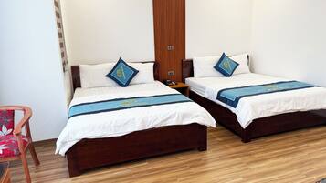 A hotel room with two wooden beds, each with a white bedspread and blue decorative pillows.
