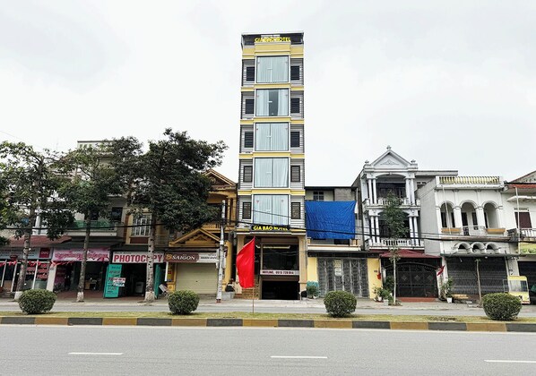 A multi-story hotel with a prominent sign, a red flag, and various storefronts along the street.