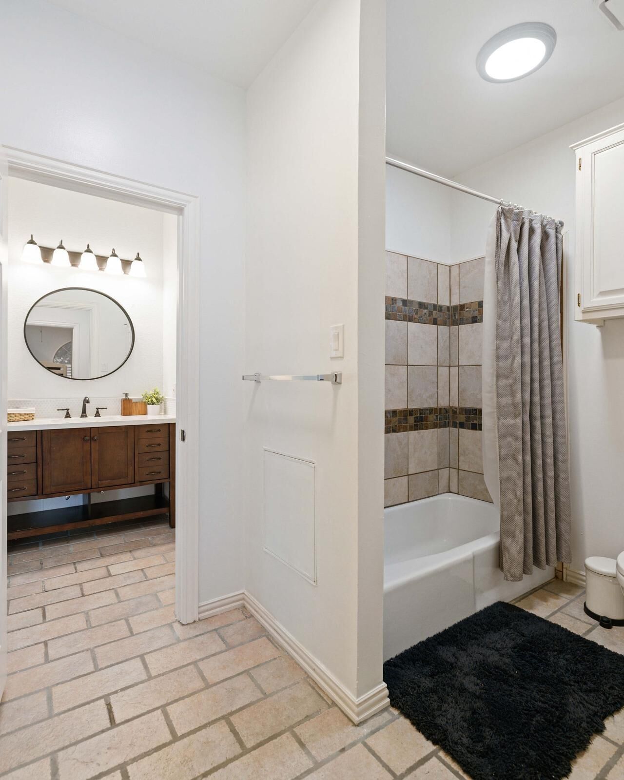 Une salle de bain équipée d’une baignoire, d’une douche et d’un meuble-lavabo avec un miroir et des luminaires.