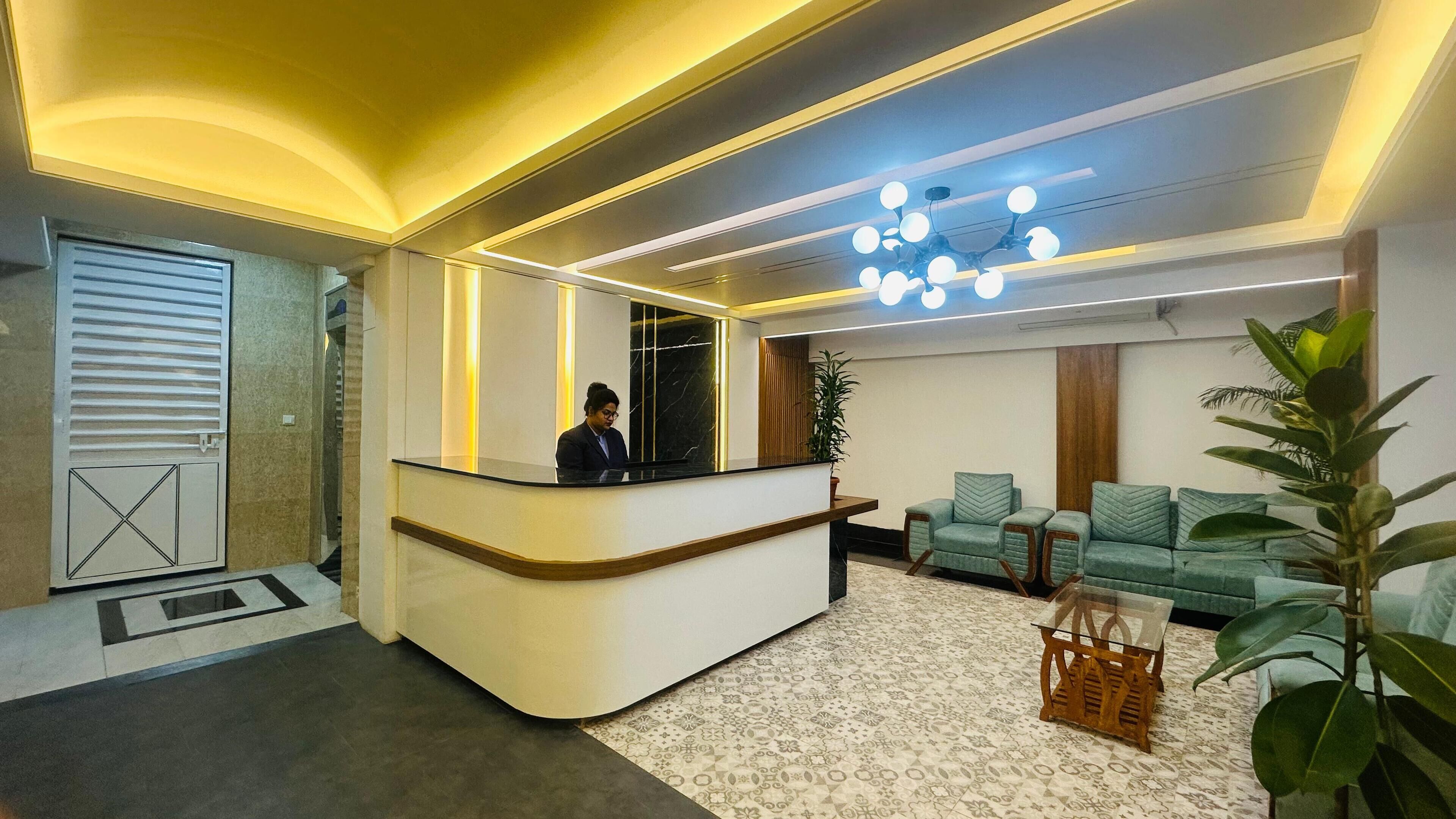 A reception area with a reception desk, a seating area with sofas, a patterned carpet, and a ceiling with recessed lighting.